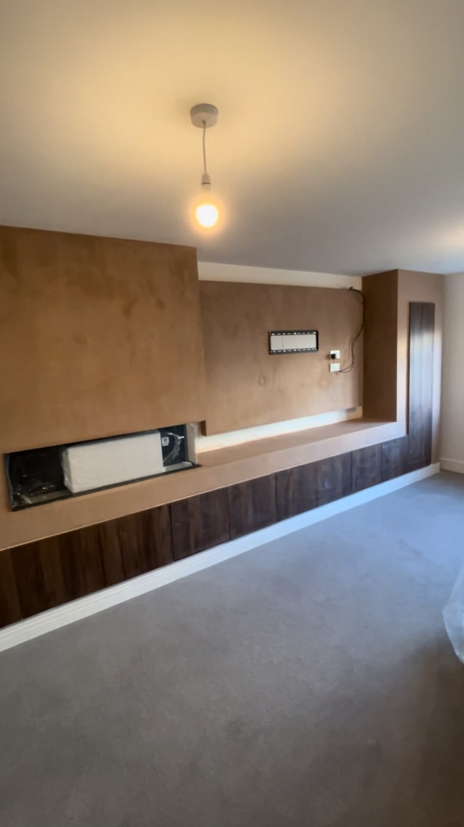 Dry lined feature wall freshly plastered around a recessed fire and fitted cabinetry